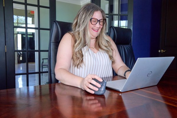 Tayla working on a laptop in a conference room with glass doors.