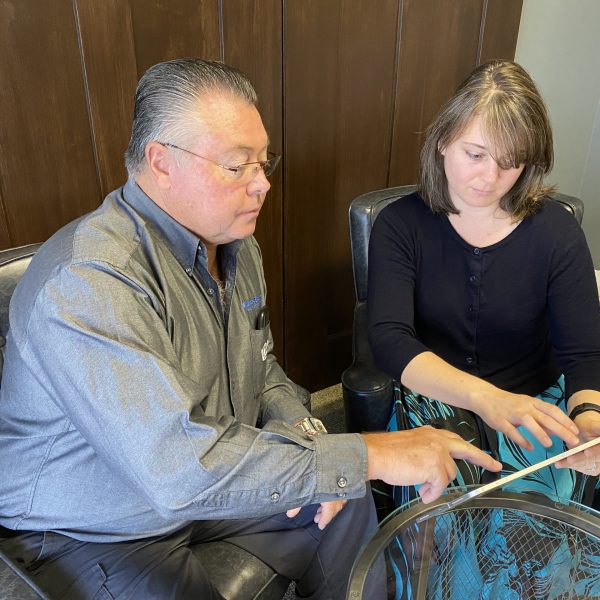 Cynthia Giles sitting with a CTM client seated in chairs collaborating while reviewing information on a tablet.