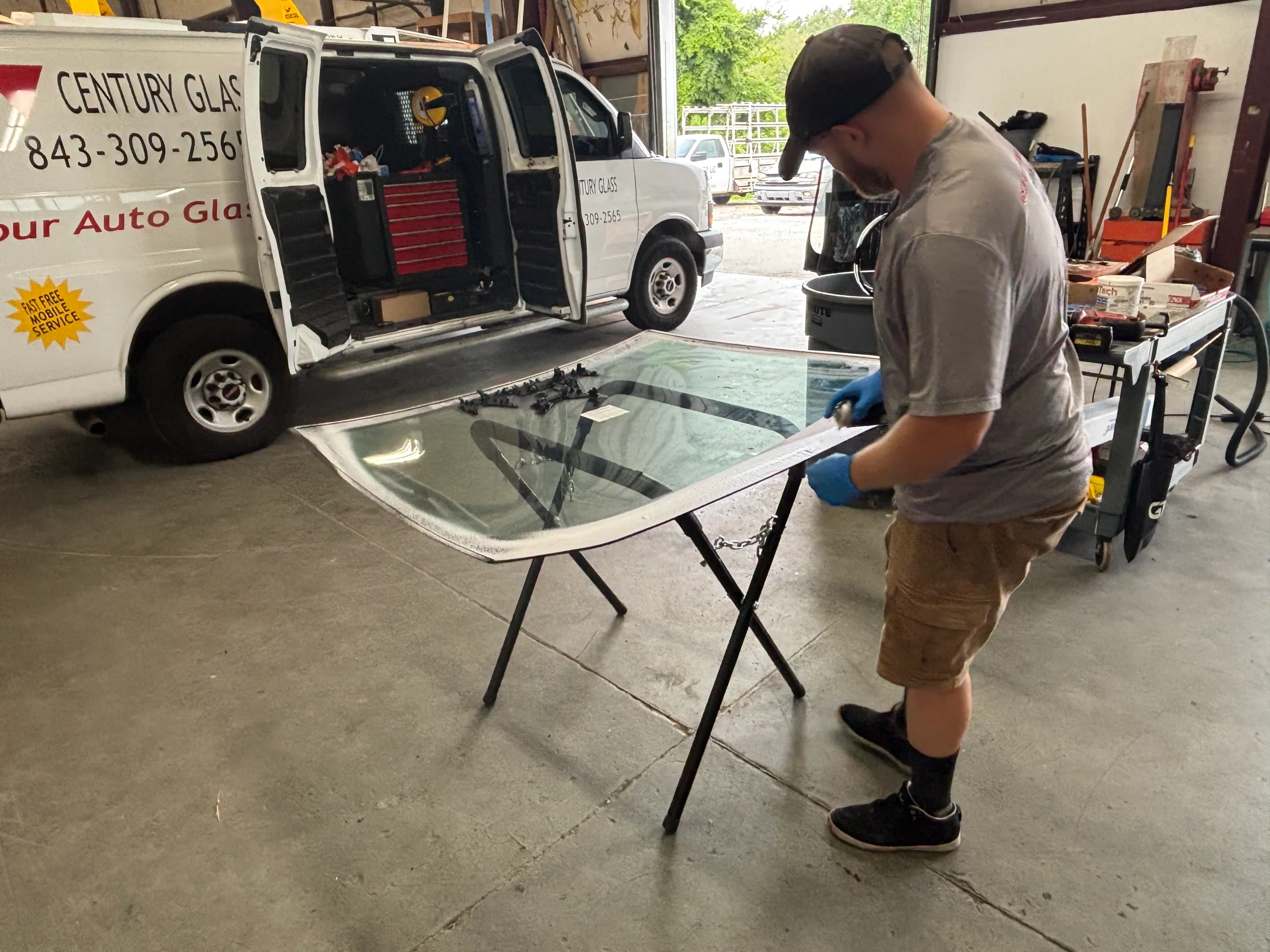 Technician replacing a windshield at an auto glass shop.